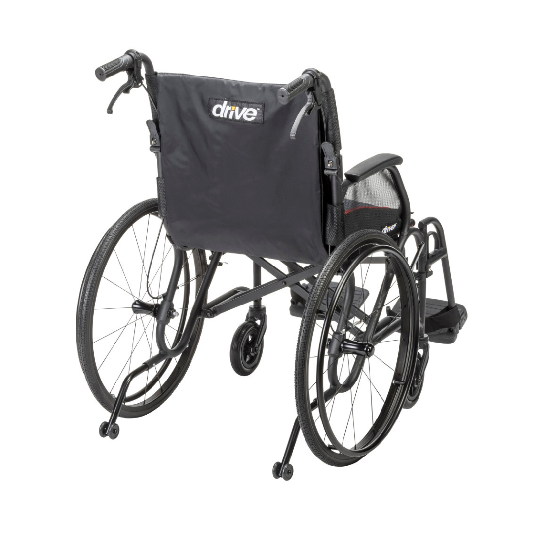 The Drive AeroFly™ Ultra-Lite Wheelchair with Companion Brakes is a black, ultra-lightweight model viewed from the back, featuring large rear wheels, small front casters, push handles, and “Drive” branding on the fabric backrest—ideal for travel.