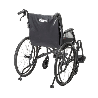 The Drive AeroFly™ Ultra-Lite Wheelchair with Companion Brakes is a black, ultra-lightweight model viewed from the back, featuring large rear wheels, small front casters, push handles, and “Drive” branding on the fabric backrest—ideal for travel.
