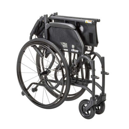 The Drive AeroFly™ Ultra-Lite Wheelchair with Companion Brakes is a lightweight, black travel chair that folds compactly for storage or transport, bringing the seat, footrests, and wheels closely together.