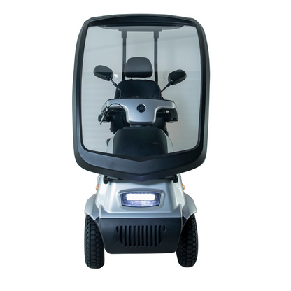Front view of the silver Afikim Afiscooter C4 HD 4-Wheel Mobility Scooter featuring a transparent windshield and enclosed cabin, four wheels, headlight, rearview mirrors, and an orthopedic seat for comfort and weather protection.