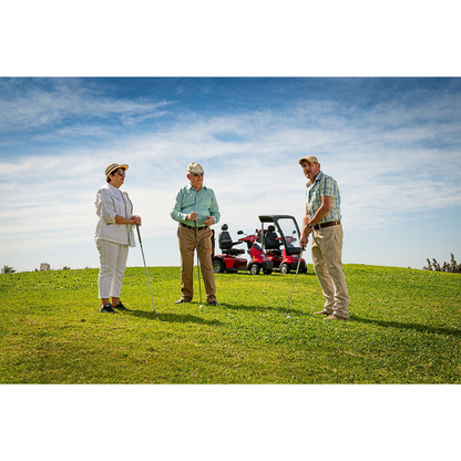 Three people in casual golf attire stand on a grassy hill with clubs. An Afikim Afiscooter Solar, recognized for its solar charging efficiency, is parked nearby, against a backdrop of blue sky and scattered clouds, emphasizing their commitment to sustainable energy on the course.
