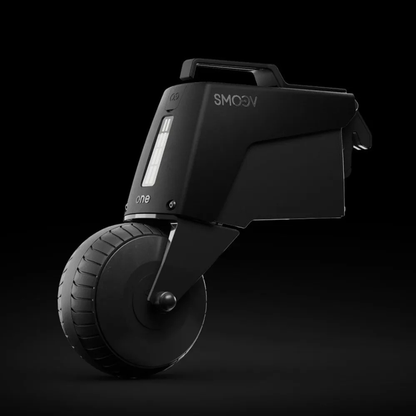 The Alber SMOOV One Power Assist, shown in sleek black with a single large wheel, digital display, and handle, enhances wheelchair mobility against a dark background.