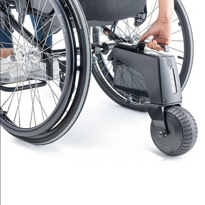 A person’s hand removes a battery from the Alber SMOOV One Power Assist attached to the rear wheel of a manual wheelchair.