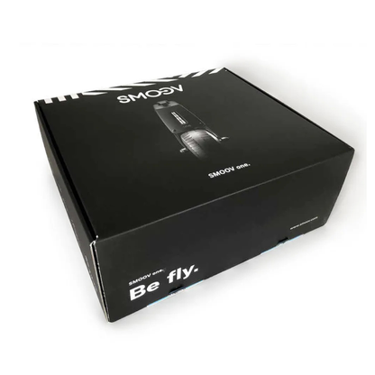 A black rectangular box with "SMOOV" and "Be fly." printed on it, featuring an image of the Alber SMOOV One Power Assist device on the lid, is shown against a white background.