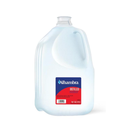 A one-gallon Alhambra Distilled Water jug has a blue handle, a red and blue label, and is mostly transparent to show the clear distilled water inside.