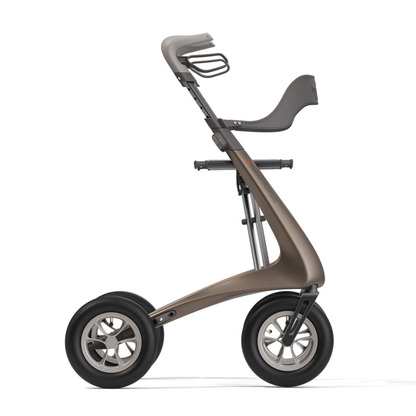 The Backrest For byAcre Overland Carbon Fiber Rollators is shown in profile on a white background, featuring a contoured seat, ergonomic handlebars, a sleek metallic frame, and two large wheels for a modern minimalist look.