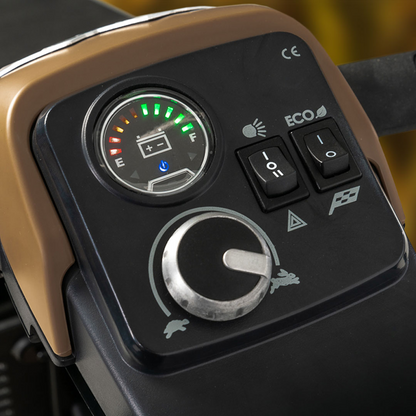 Close-up of the Pride Baja® Bandit 4 Wheel Scooters dashboard, showcasing a fuel gauge, toggle switches, and a large control dial. Designed for off-road excursions, it features symbols like a rabbit and turtle for varied terrain settings.
