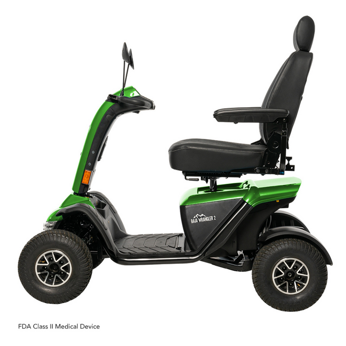 The Pride Baja® Wrangler® 2 Heavy Duty Outdoor Scooter is green with a black seat and handlebar, designed for rugged terrain. It has four large tires, side mirrors, adjustable armrests and backrest, advanced CTS Suspension for a smoother ride, and an FDA Class II Medical Device label.
