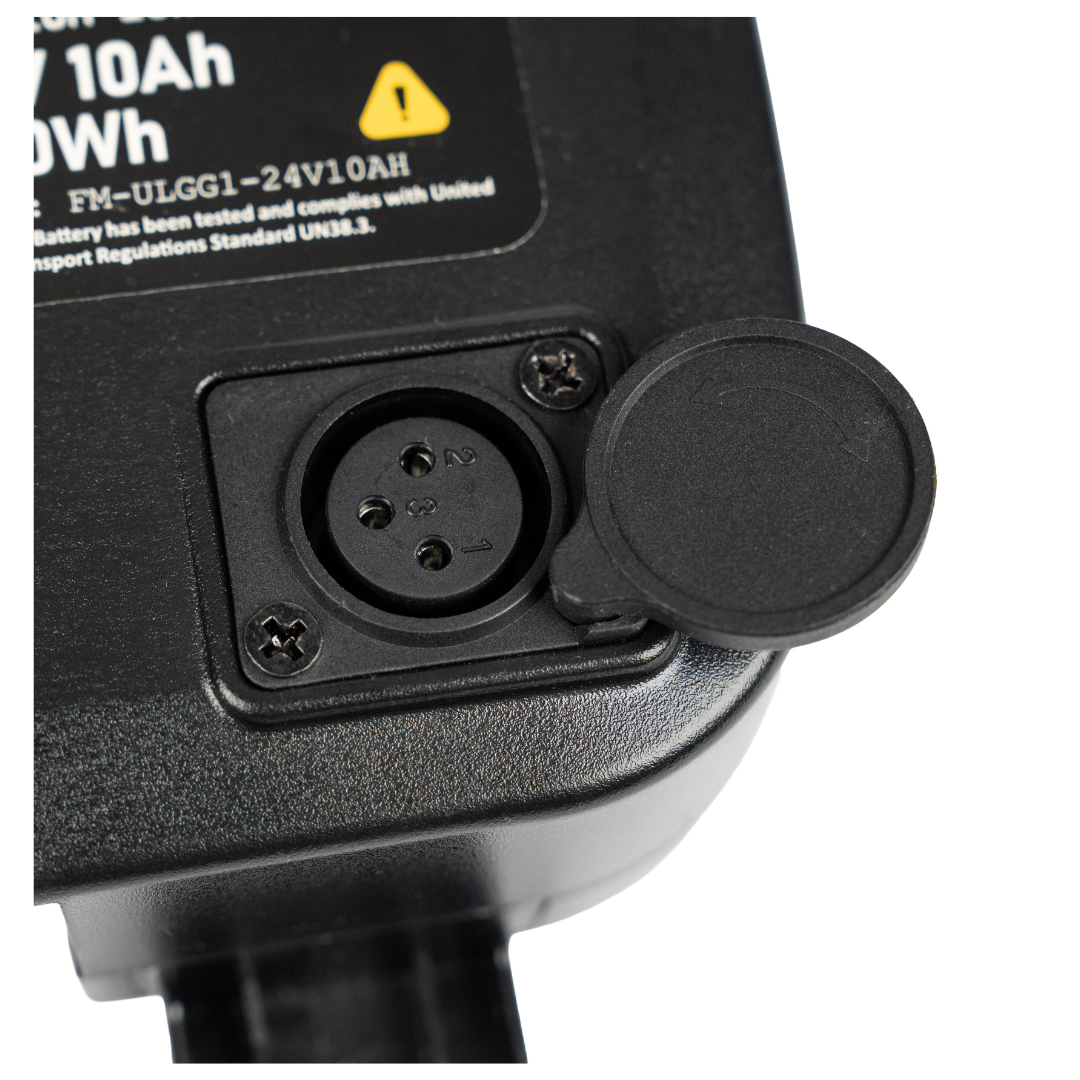 Close-up of a black three-pin electrical socket with a hinged cover, attached to a device labeled with battery and voltage details—compatible with the Forcemech Replacement Battery for G10 Carbon Powerchair.