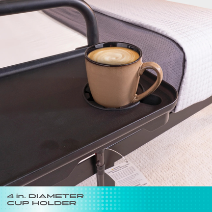 A brown coffee mug with latte art rests in a 4 in. diameter cup holder on the Stander Bed Rail Tray Accessory, which is attached to a bed with white bedding. Text on the image reads: 4 in. DIAMETER CUP HOLDER.
