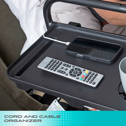 A Stander Bed Rail Tray Accessory holds a smartphone with a white cord organizer, a TV remote, and a gray mug. The black tray attaches to a chair or bed rail. “Cord and Cable Organizer” appears at the bottom.