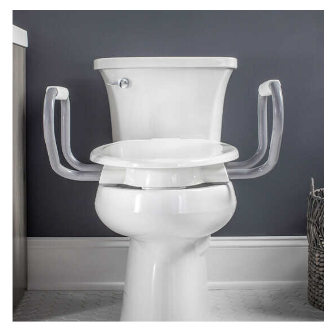 The Bemis Assurance® with Clean·Shield 3 Premium Raised Toilet Seat, in white and equipped with support arms for safety, sits against a gray wainscoted wall for elegance. A wicker basket to the right adds functional style.