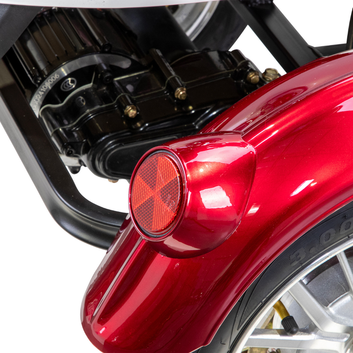 Close-up of a shiny red fender with a round red reflector on the Bespoke Supreme Euro-Style Recreational 3-Wheel Scooter, showing part of the rear wheel, suspension system, and electric brake assist technology in the background.