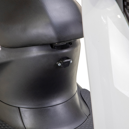 Close-up of the under-seat area on the black and white Bespoke Supreme Euro-Style Recreational 3-Wheel Scooter with Electric Brake Assist, featuring its locking mechanism, part of the footrest, and advanced technology details.