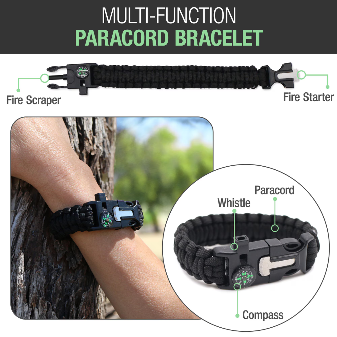 A black paracord bracelet with fire starter, scraper, compass, and whistle—shown outdoors—is the ideal companion to your Brazos First Aid Survival Kit - 250 Pieces. Compact multi-function survival tools always at hand.