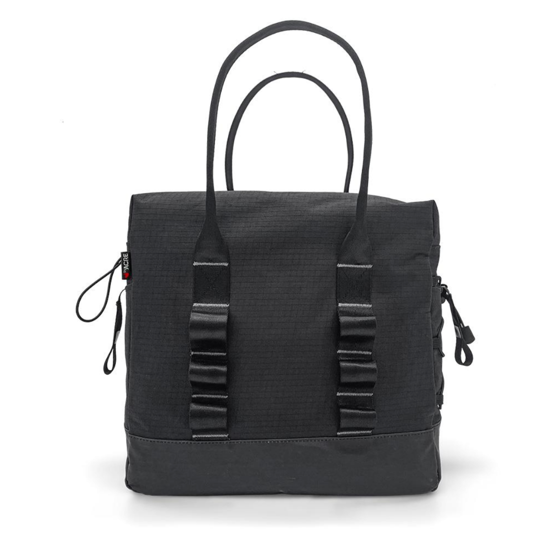 The ByAcre Accessories for Overland Carbon Fiber Rollators features a chic black tote bag with two top handles. Its minimalist, textured design is complemented by side zippers and loop details, offering a sturdy square shape that combines functionality and modern style.