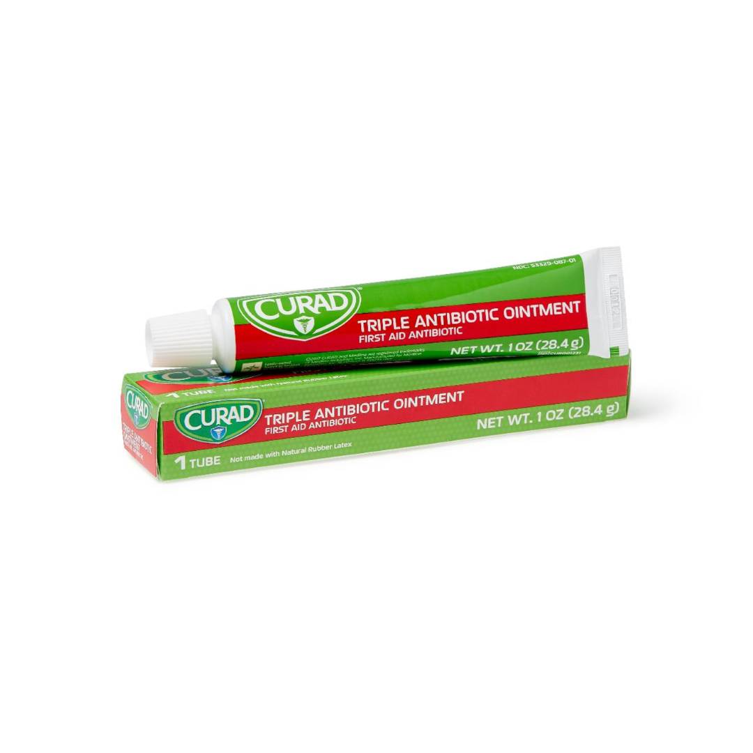 A tube of Medline CURAD Triple Antibiotic Ointment rests on its green and red box, featuring labels like hospital-quality protection, First Aid Antibiotic, and a net weight of 1 oz (28.4 g).