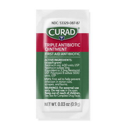 A small white packet of Medline CURAD Triple Antibiotic Ointment with green and red labeling lists active ingredients, usage instructions, and warnings. Each 0.03 oz (0.9g) packet offers hospital-quality protection.