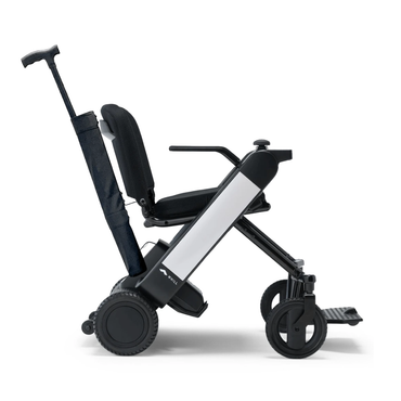 A Cane Holder for the WHILL Model F Powerchair is shown attached to the side of this modern, compact foldable wheelchair, featuring large rear wheels, a slim frame, a collapsible backrest, and an extendable handle for easy transport.