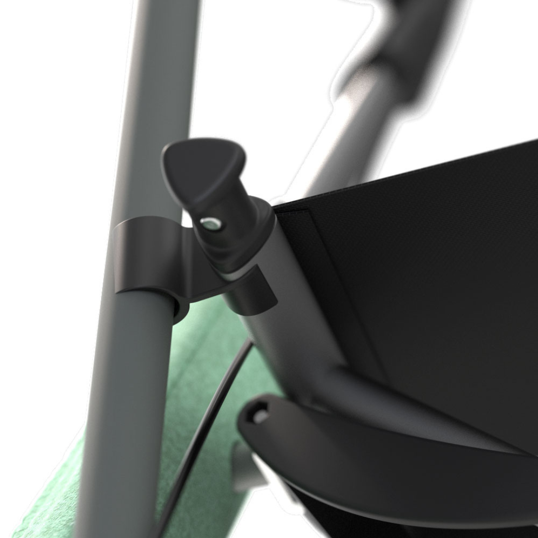 Close-up of a black lever and clamp mechanism from the Cane Holder For byACRE Nordic Pioneer Rollator, attached to a metal pole with green fabric in the background.