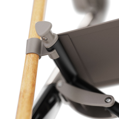 Close-up of a joint mechanism on a modern chair, with a light wooden armrest attached to a metal and fabric frame using a sleek, matte gray connector—similar to the Cane Holder for ByAcre Ultralight Carbon Fiber Rollators.