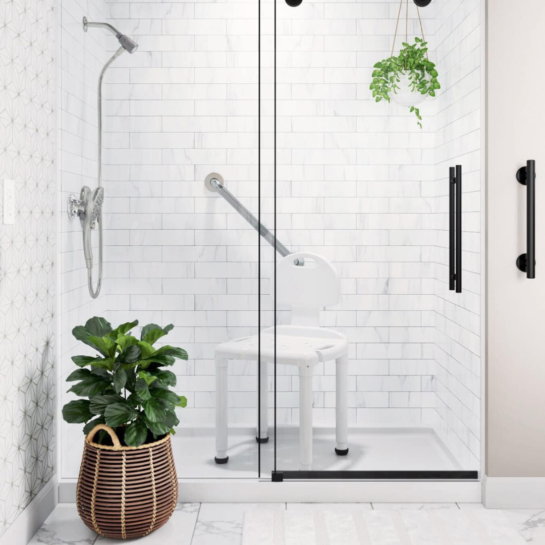 A modern shower with white subway tiles, glass door, wall-mounted showerhead, grab bar, hanging plant, woven basket with green potted plant, and a Carex Bariatric Bath Seat And Shower Chair with Backrest for seniors.