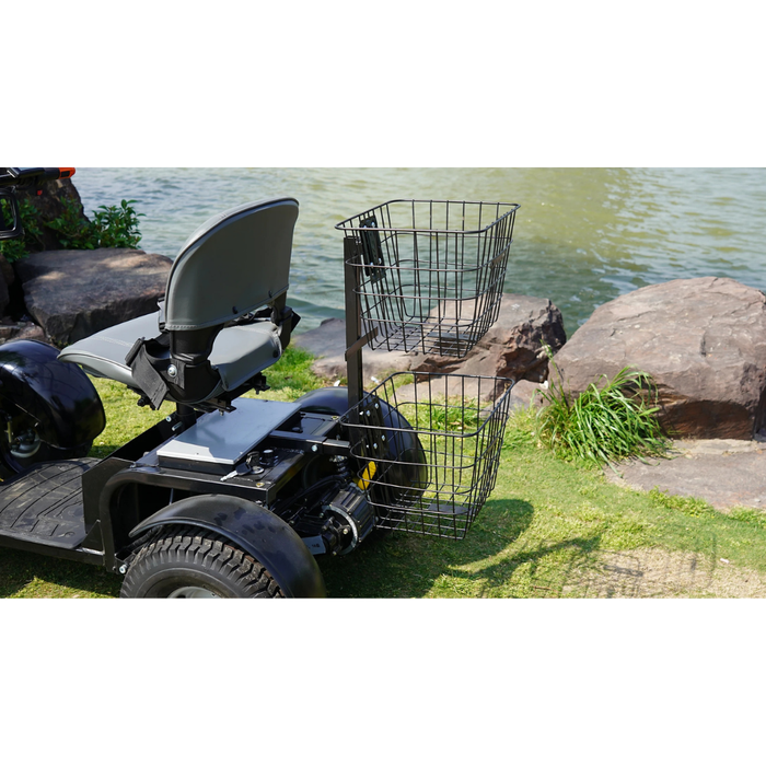 A Green Transporter Cheeta Ninja All-Terrain HD Scooter Golf Cart is parked on grass by the water, with two wire baskets mounted on a rear pole. Rocks and plants run along the water’s edge in the background.