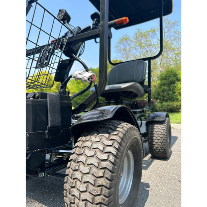 Close-up of a black Green Transporter Cheeta Ninja All-Terrain HD Scooter Golf Cart with large rugged tires on pavement. A front basket is visible, with green trees and a clear blue sky in the background.