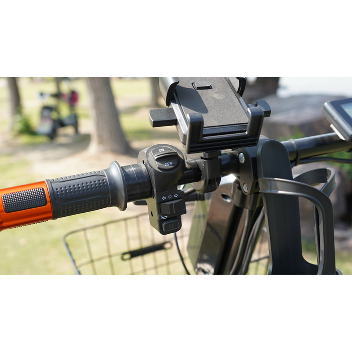 Close-up of the Green Transporter Cheeta Ninja All-Terrain HD Scooter Golf Cart handlebar, featuring a mounted phone holder, on/off control switch, and basket—showcasing all-terrain capability with a blurred park and trees behind.