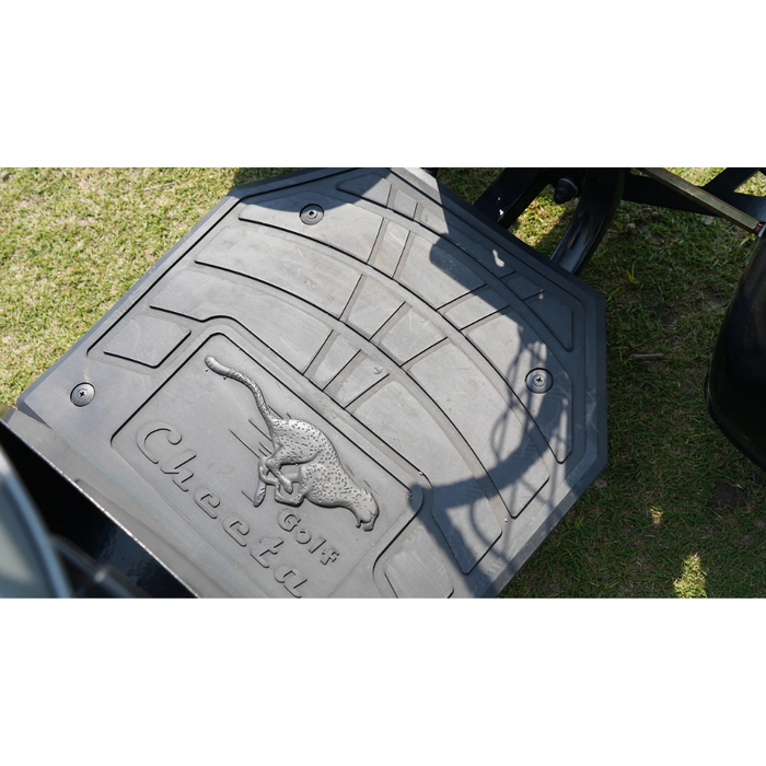 Close-up of a black rubber mat on grass, embossed with a cheetah and the text Golf Cheetu—evoking the all-terrain performance of the Green Transporter Cheeta Ninja All-Terrain HD Scooter Golf Cart. Shadows partially cover the mat.