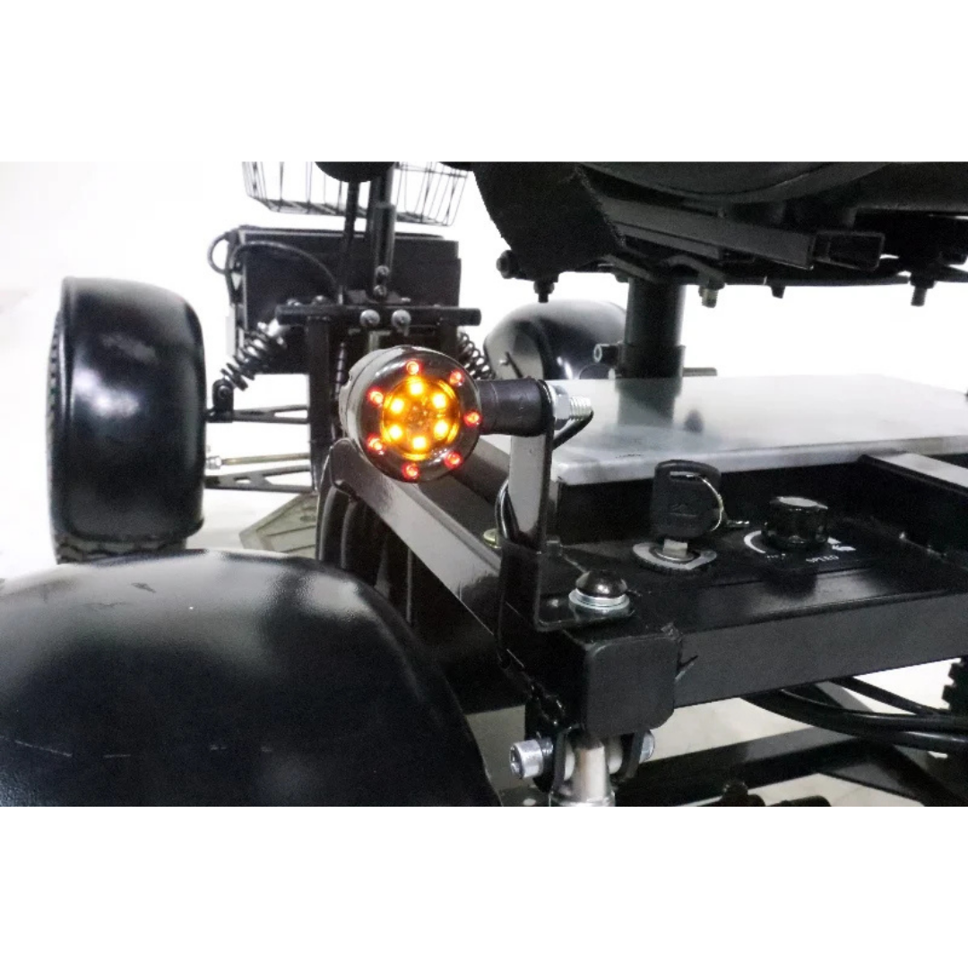 Close-up of the Green Transporter Cheeta Ninja All-Terrain HD Scooter Golf Cart’s rear, showing its illuminated orange circular tail light, sturdy frame detail, and large black wheels designed for all-terrain use.
