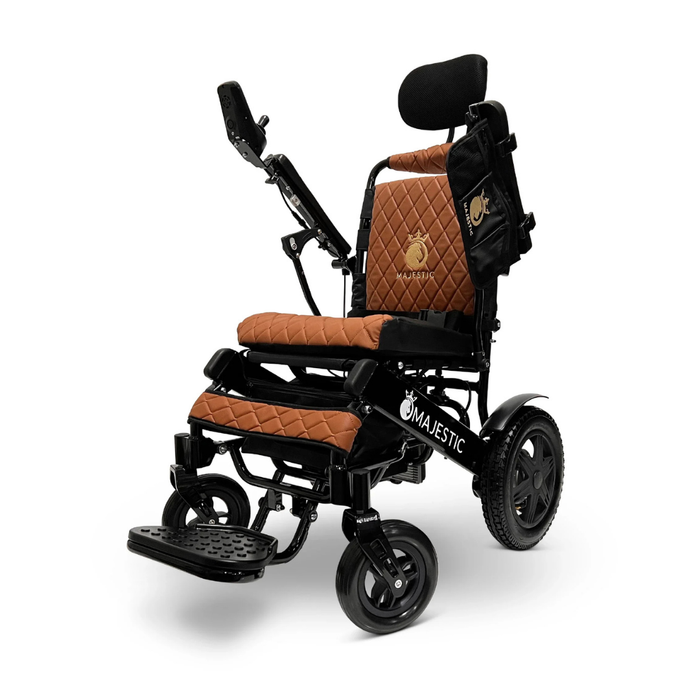 The ComfyGo MAJESTIC IQ-9000 is a modern electric wheelchair with a black frame, brown quilted seat and backrest, digital joystick controller, adjustable leg supports, headrest, side bag, and Majestic branding on the lower frame.