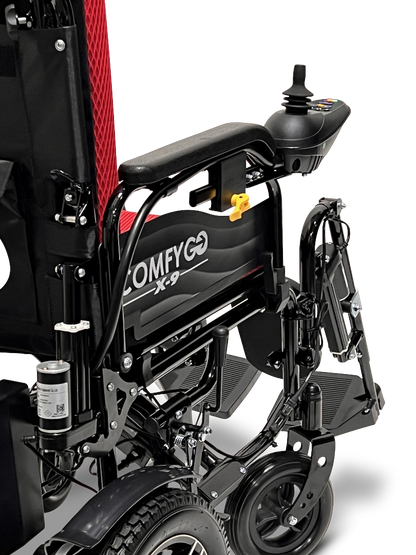 Close-up view of the black and red ComfyGo X-9 Remote Controlled Powerchair, featuring its backrest, armrest, joystick controller, and wheel part. This remote-controlled mobility solution highlights the powerchairs design and features.