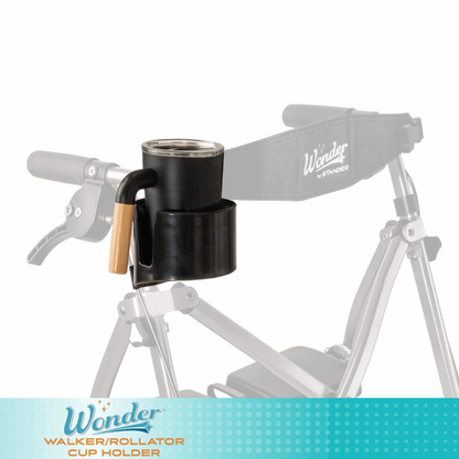 A Cup Holder For Stander Walkers & Rollators with a wooden handle is attached to a silver walker, holding a cup. Blurred walker handles and a Wonder by Stander strap appear in the background.