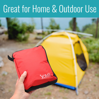 A hand holds the DMI 298-Piece Complete Emergency First Aid Kit outdoors, with a yellow tent and greenery in the background. Text above reads, “Great for Home & Outdoor Use.”.