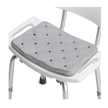 The DMI Waterproof Foam Bath Seat Cushion, gray and quilted with small ventilation holes for slip prevention, is shown on a white shower chair with armrests and metal legs.