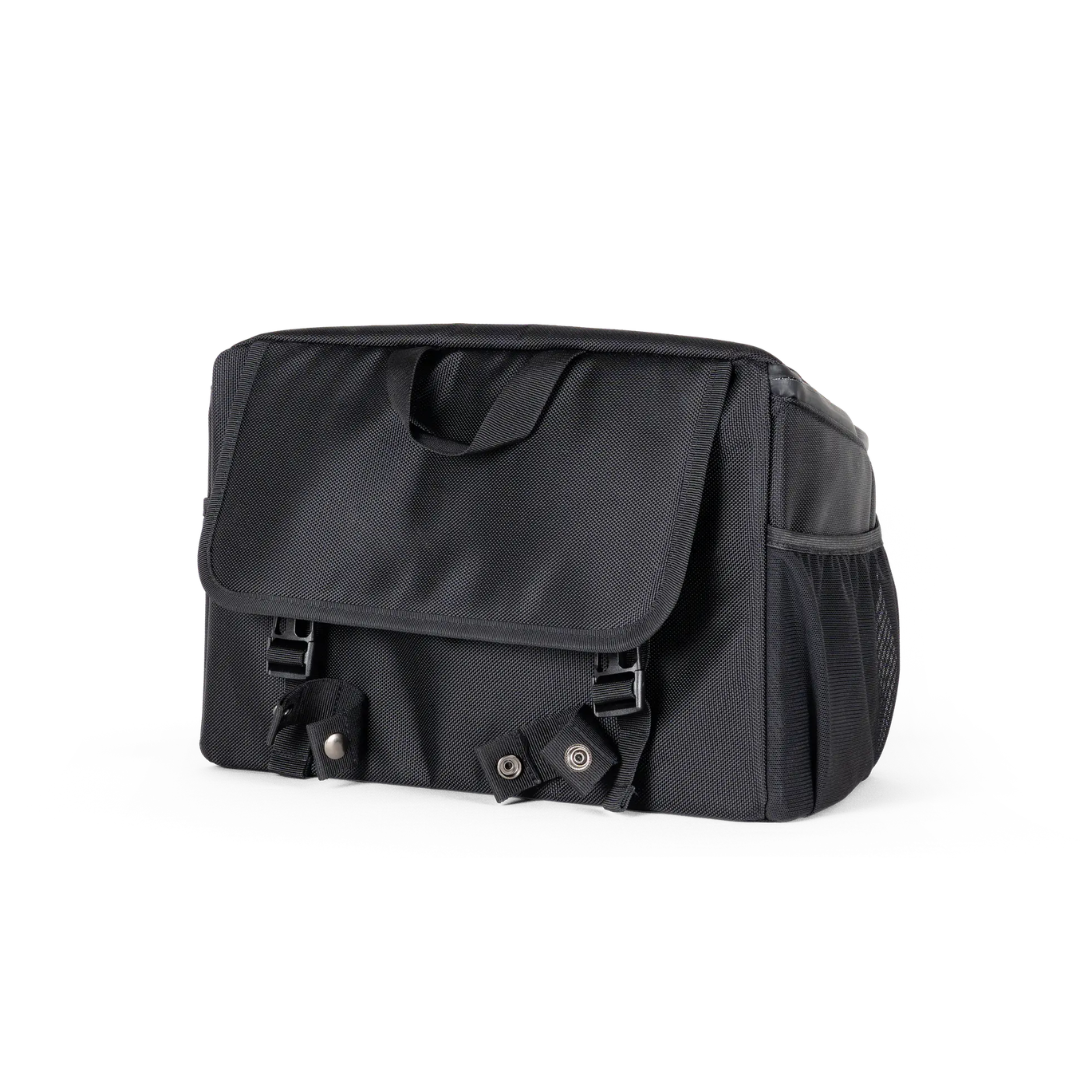 The Saddle Bag for Dashmoto Dash 3 Scooter features a black rectangular shape with a top handle, front flap secured by dual snap buckles, and a convenient side mesh pocket. Its simple yet functional design is crafted from durable fabric, making it the perfect mobility accessory for use with the Dashmoto Dash 3 scooter.