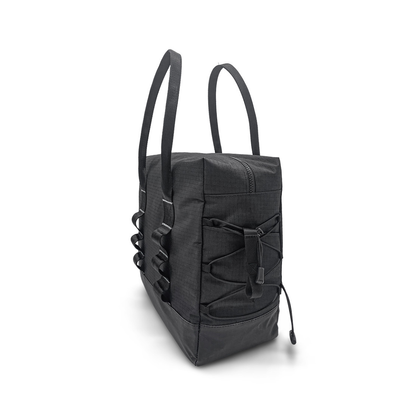 The Daypack For ByAcre Carbon Fiber Rollators is a black rectangular tote with long handles, side loops, and a front bungee cord. Stylish and practical, it doubles as a rollator backpack for essentials. Shown upright on a white background.