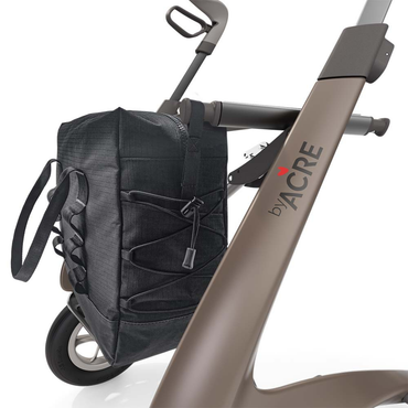 A close-up of a byACRE Carbon Fiber Rollator with the Daypack attached. The practical mobility bag features handles and bungee cords, and the rollator bears the byACRE logo with a small red heart above the A.