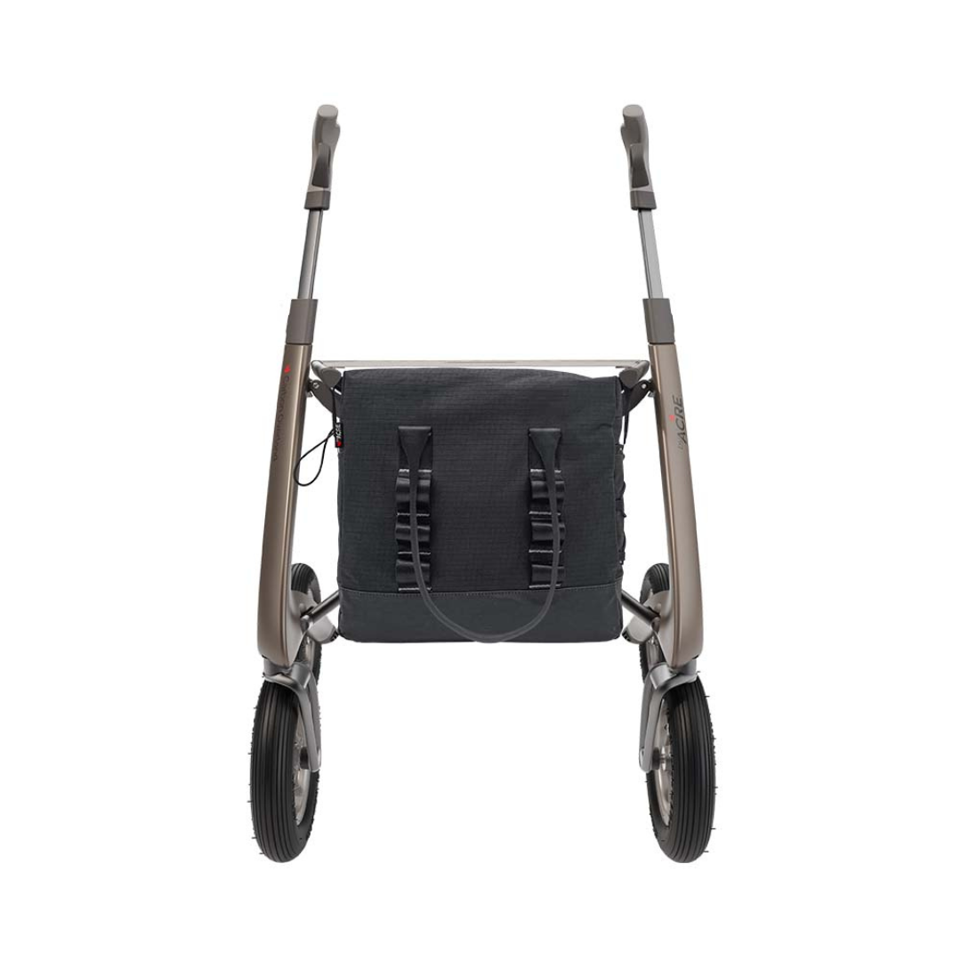 A modern, lightweight rollator walker with two large front wheels, ergonomic handles, and a Daypack For ByAcre Carbon Fiber Rollators backpack attached between the frame legs, seen from the front.