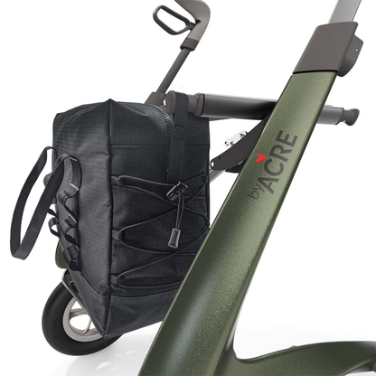 Close-up of a green ByAcre Carbon Fiber Rollator with the Daypack attached to its side. Features include sturdy handles, large wheels, a bungee cord securing the Daypack, and "by ACRE" text on the frame.