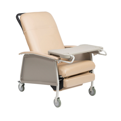 The Drive 3-Position Geri-Chair Recliner with Wheels is a beige medical chair with armrests, a foldable tray table, and four wheels for mobility, designed to provide comfort in healthcare settings.