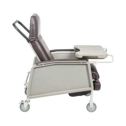 A side view of the Drive 3-Position Geri-Chair Recliner with Wheels, featuring brown cushions, a grey frame, wheels, and a beige tray on the right armrest—designed for comfortable patient care.