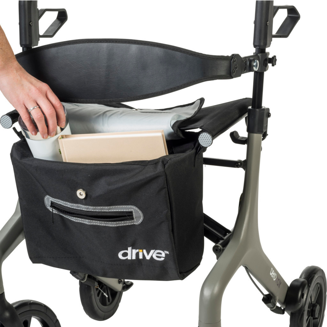A person stores a folder and cushion in a black bag attached to the Drive AeroWalk Ultra-Lite Rollator, enhancing mobility support.