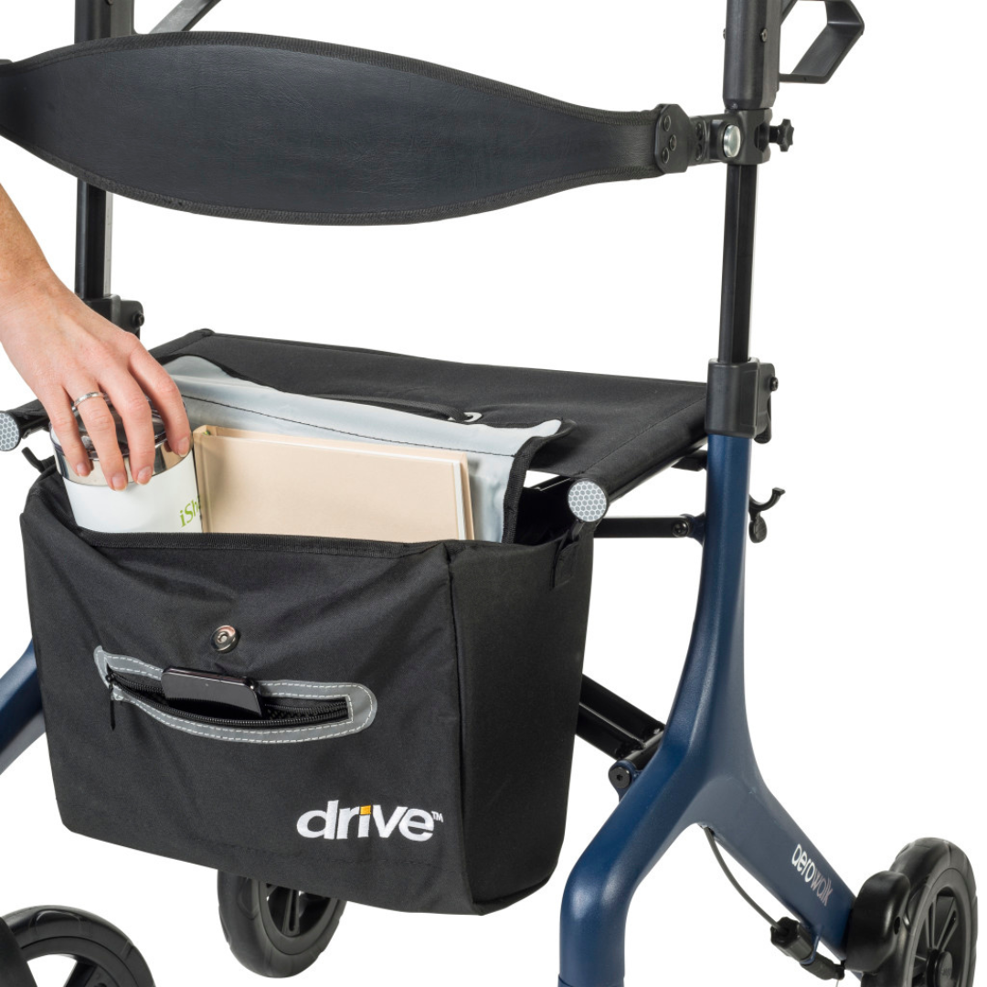 A hand places documents into a black storage bag with a front pocket and Drive logo, attached to the blue Drive AeroWalk Ultra-Lite Rollator, providing convenient mobility support.