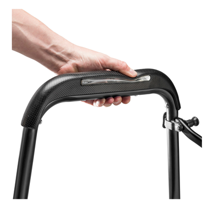 A hand grips the curved, cushioned handle of the Drive Air-Go Walker with Airgonomic™ Hand Comfort & Seat, showing its metal nameplate against a plain white background.
