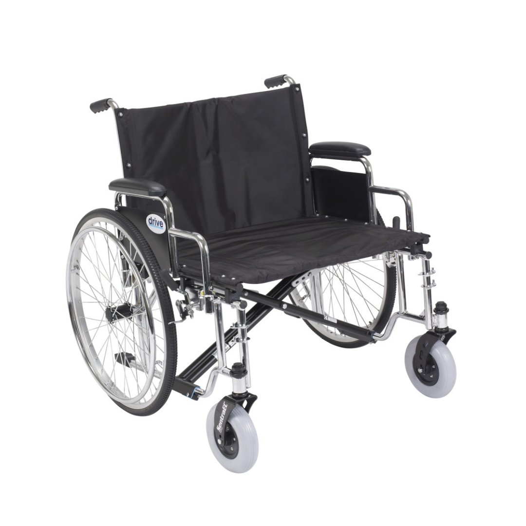 The Drive Bariatric Sentra EC Heavy-Duty Extra-Wide Wheelchair features a black and silver frame, large rear wheels, small front wheels, armrests, footrests, and supports up to 700 lbs for reliable mobility assistance.