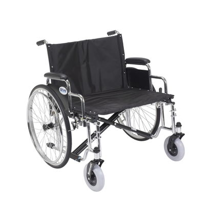 The Drive Bariatric Sentra EC Heavy-Duty Extra-Wide Wheelchair features a black and silver frame, large rear wheels, small front wheels, armrests, footrests, and supports up to 700 lbs for reliable mobility assistance.
