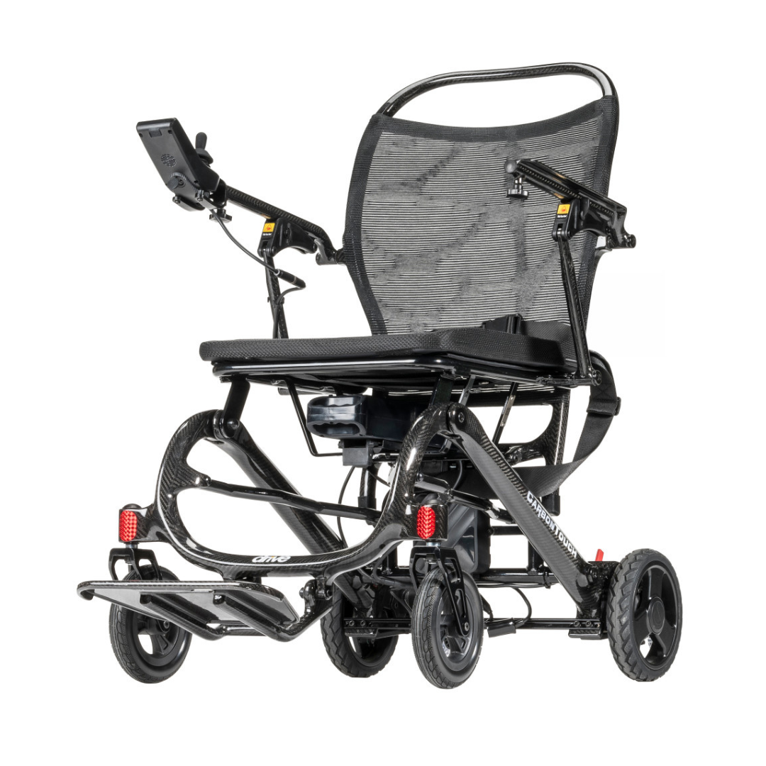 The Drive CarbonTouch Power Wheelchair is a lightweight model featuring a sleek black design, mesh backrest, small front and rear wheels, convenient footrests, and an intuitive hand control panel on the armrest.