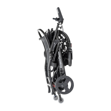 A black lightweight power wheelchair folded upright for transport or storage, with the label CARBON TOUCH visible on the frame and small wheels at the base. This is the innovative Drive CarbonTouch Power Wheelchair, designed for both convenience and portability.